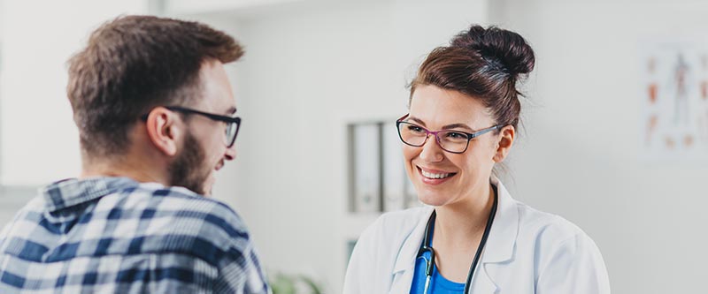 A doctor speaks and smiles at a patient